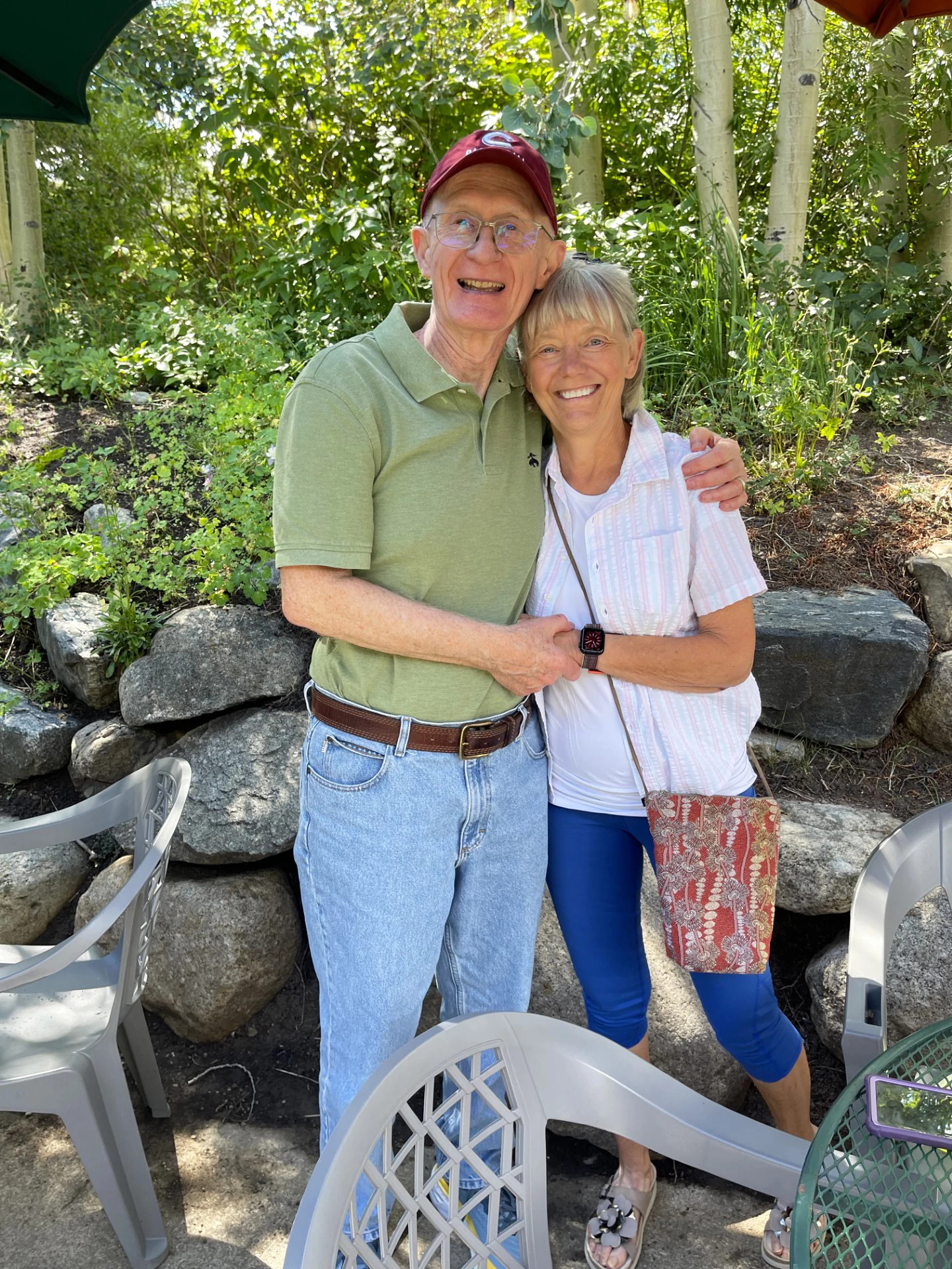 two people standing outside by a wall of rocks