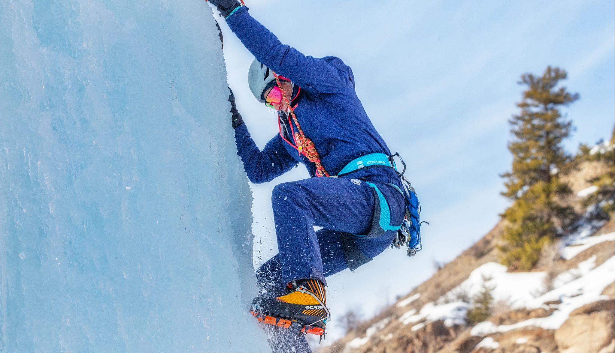 Veteran Expeditions a person climbs an ice-covered cliff