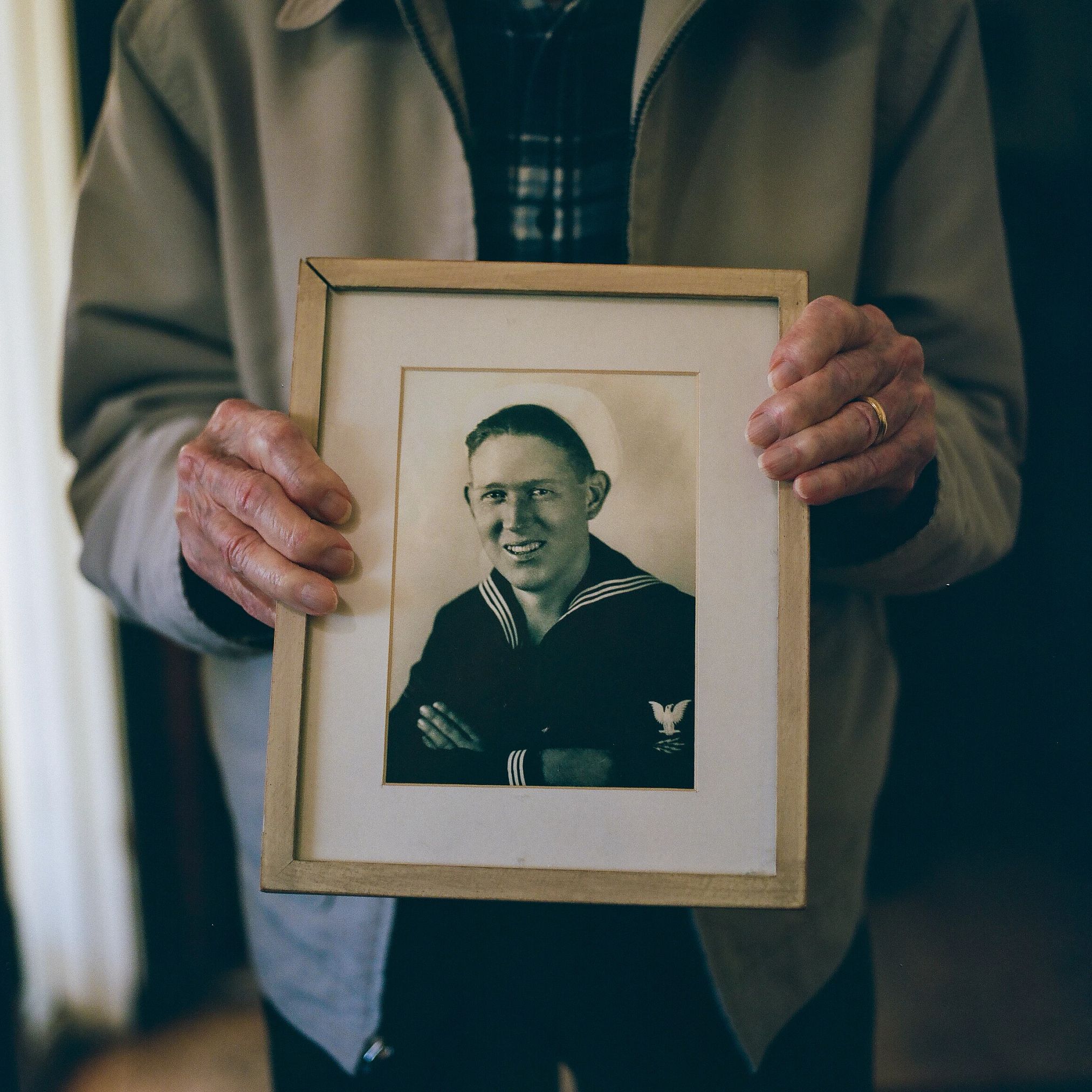 Warren Upton hands hold a framed portrait of a sailor