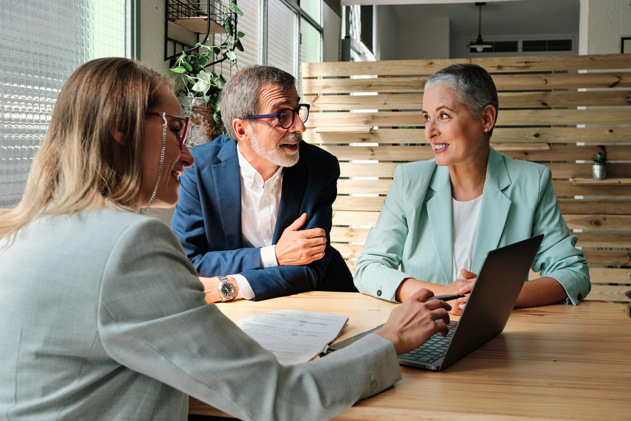 two people talk with a financial planner, who is pointing at a laptop