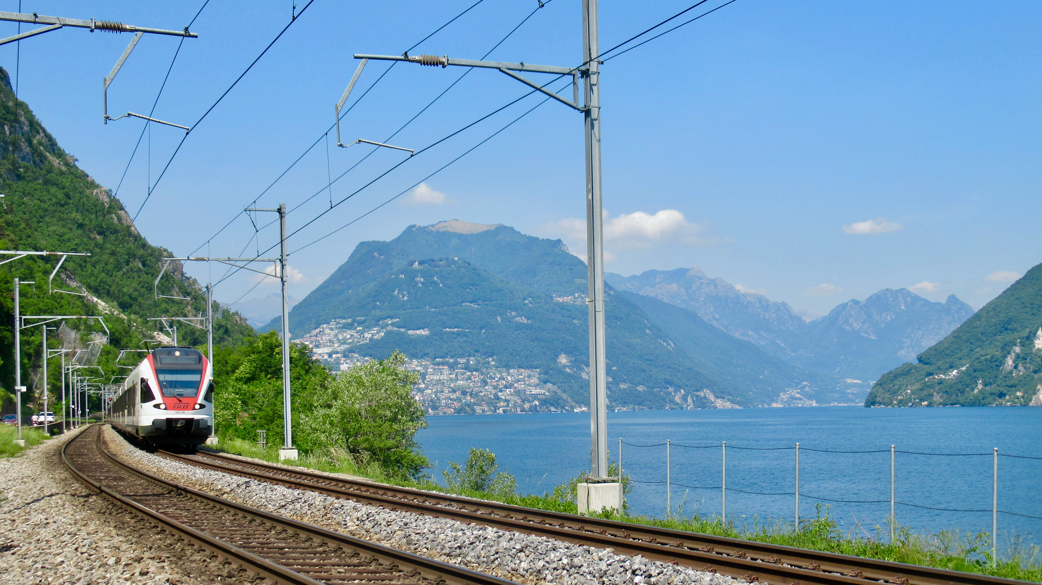 a train traveling near a lake with mountains in the background