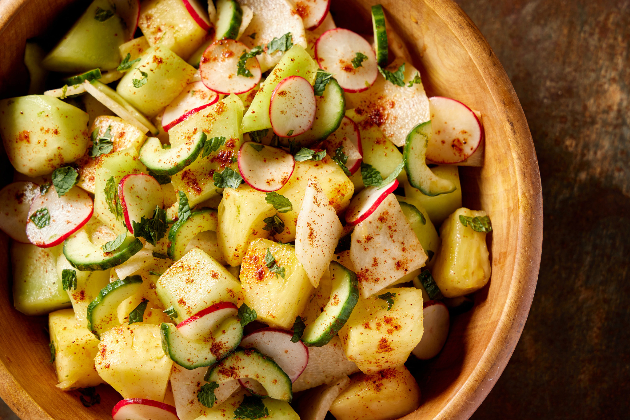 A chili-lime pineapple and honeydew salad is pictured in a bowl atop a countertop