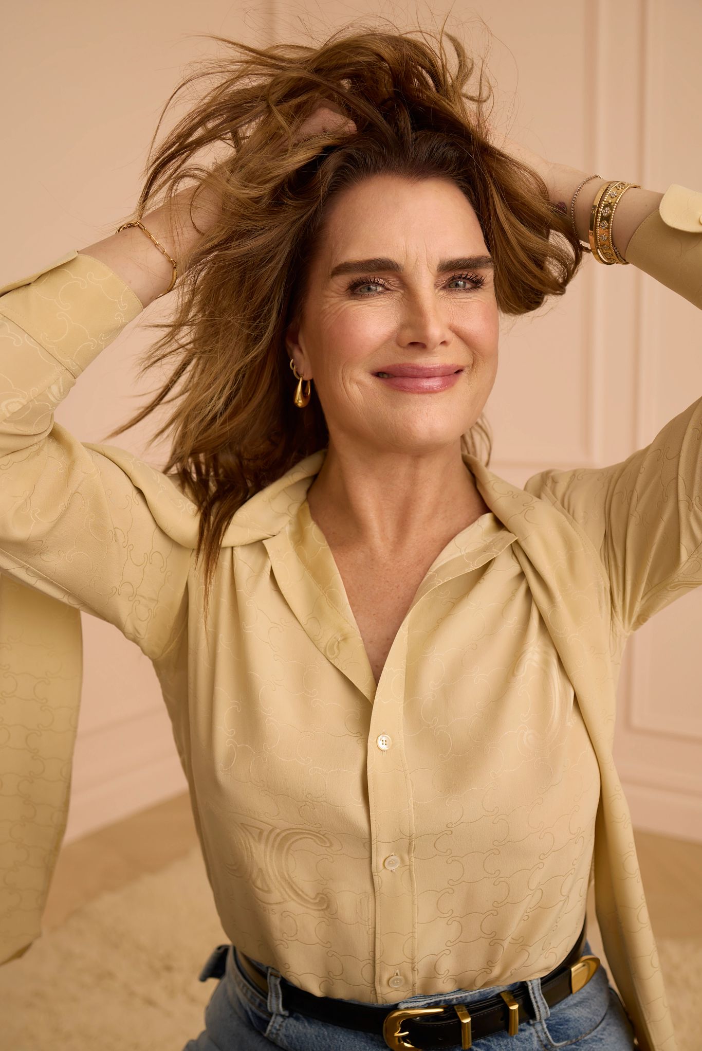 Brooke Shields smiling with her hands playing with her hair 