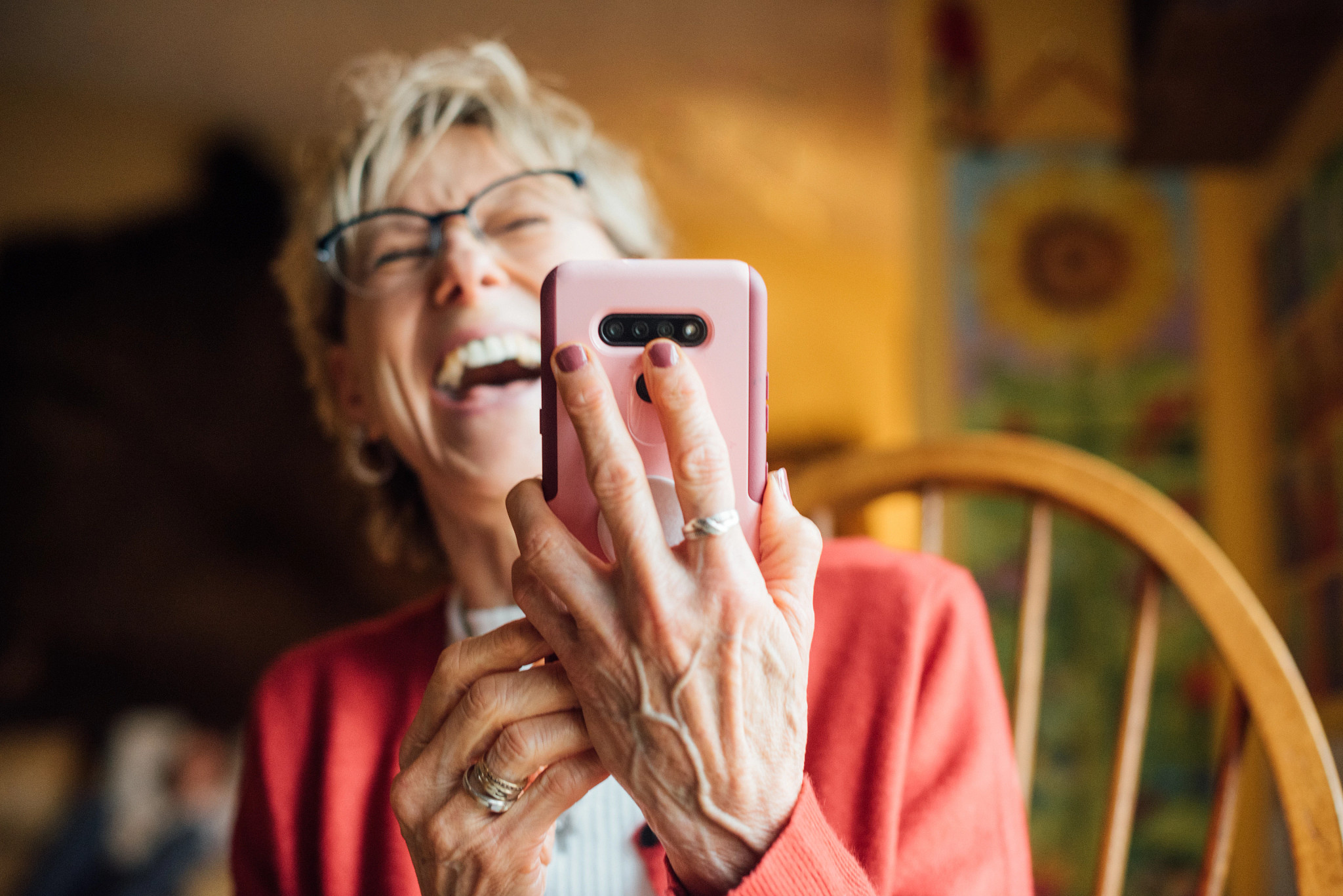 Age 50+ woman laughing while enjoying a cellphone app.