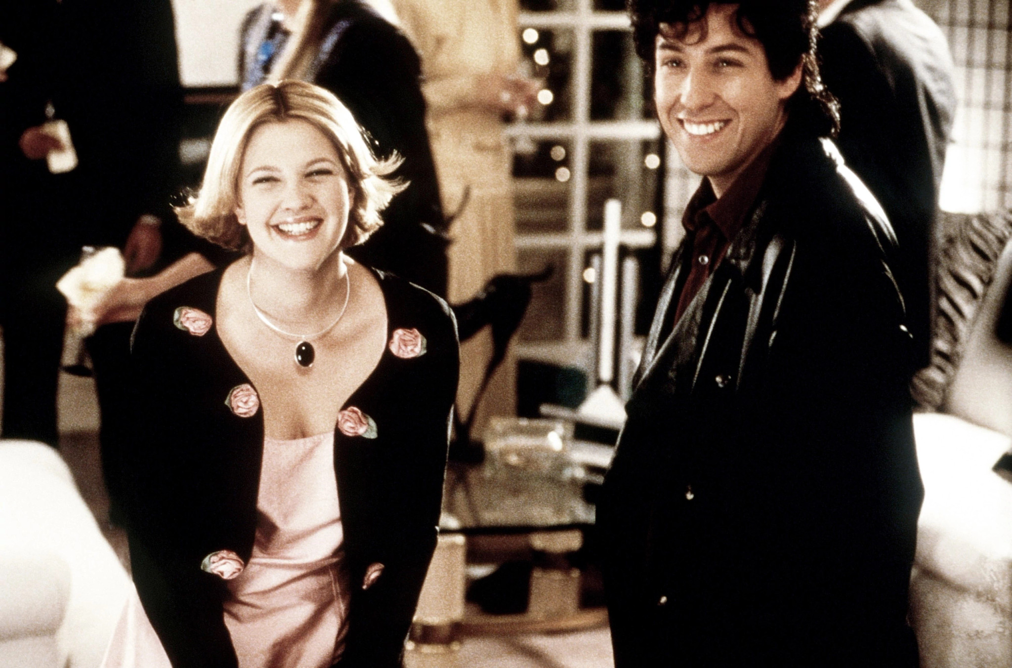 Drew Barrymore and Adam Sandler smiling together in a scene from the movie "The Wedding Singer"