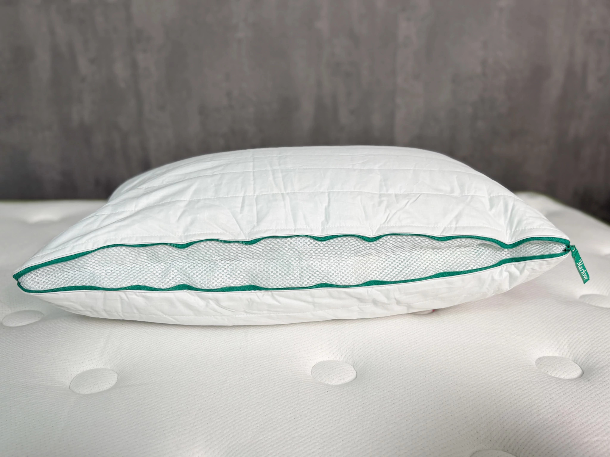 The Brooklinen Marlow Pillow lying on a mattress with a side panel unzipped