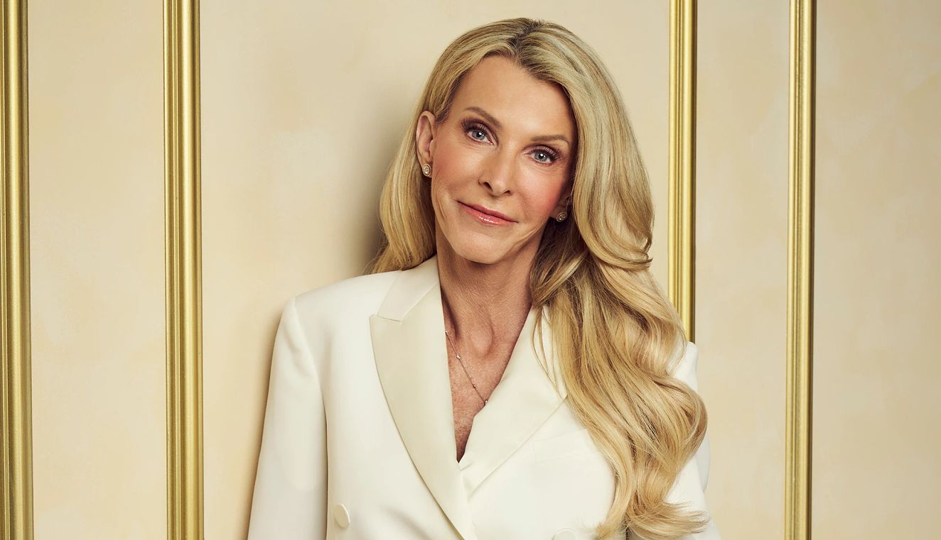 The Golden Bachelorette Joan Vassos The Golden Bachelorette Joan Vassos holding a golden rose while leaning against a wall