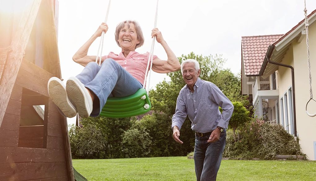 Do something playful and fun to revisit the ease of childhood A woman on a swing being pushed from behind by a man
