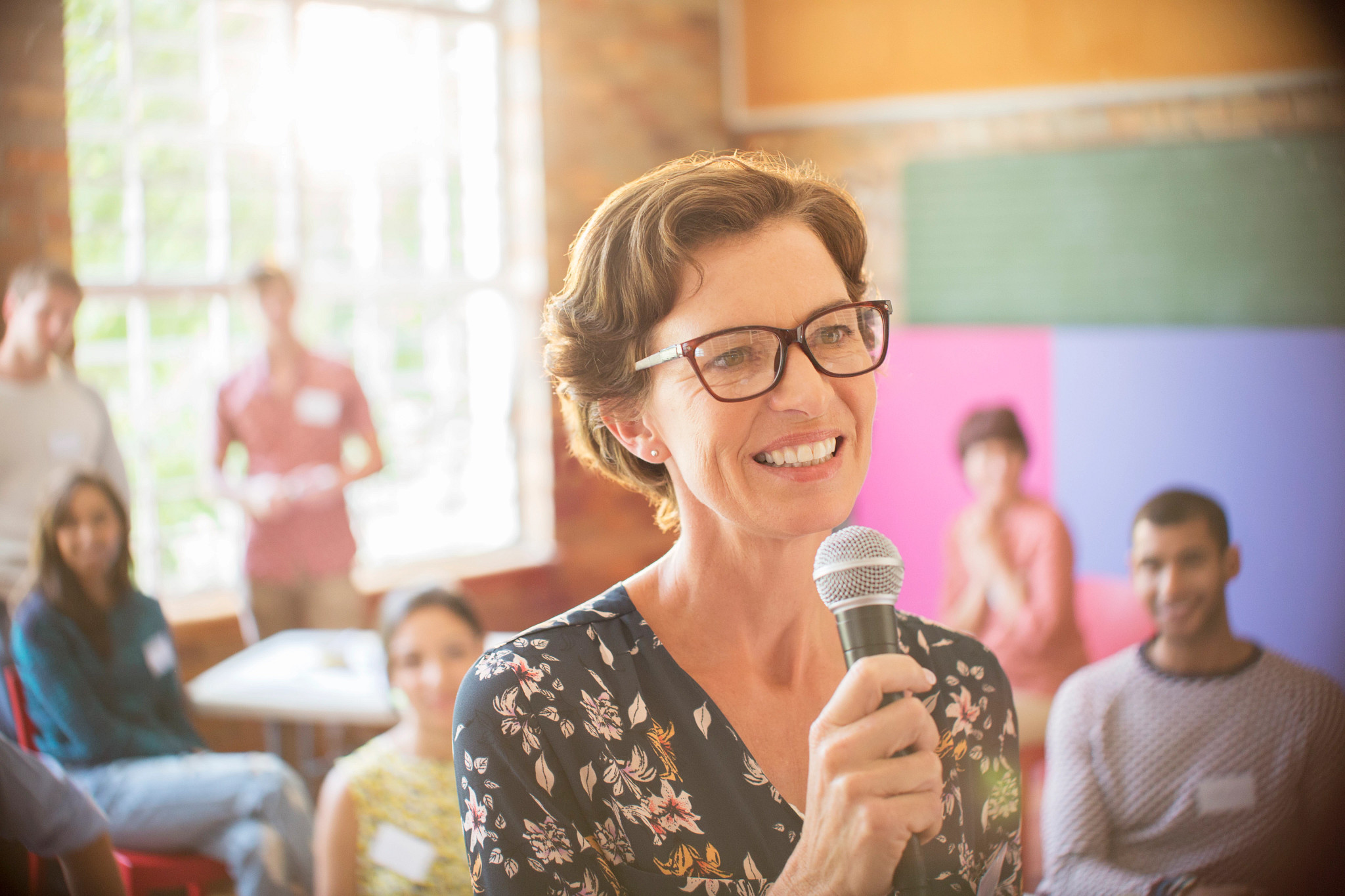 Audience behind smiling speaker with microphone at community center