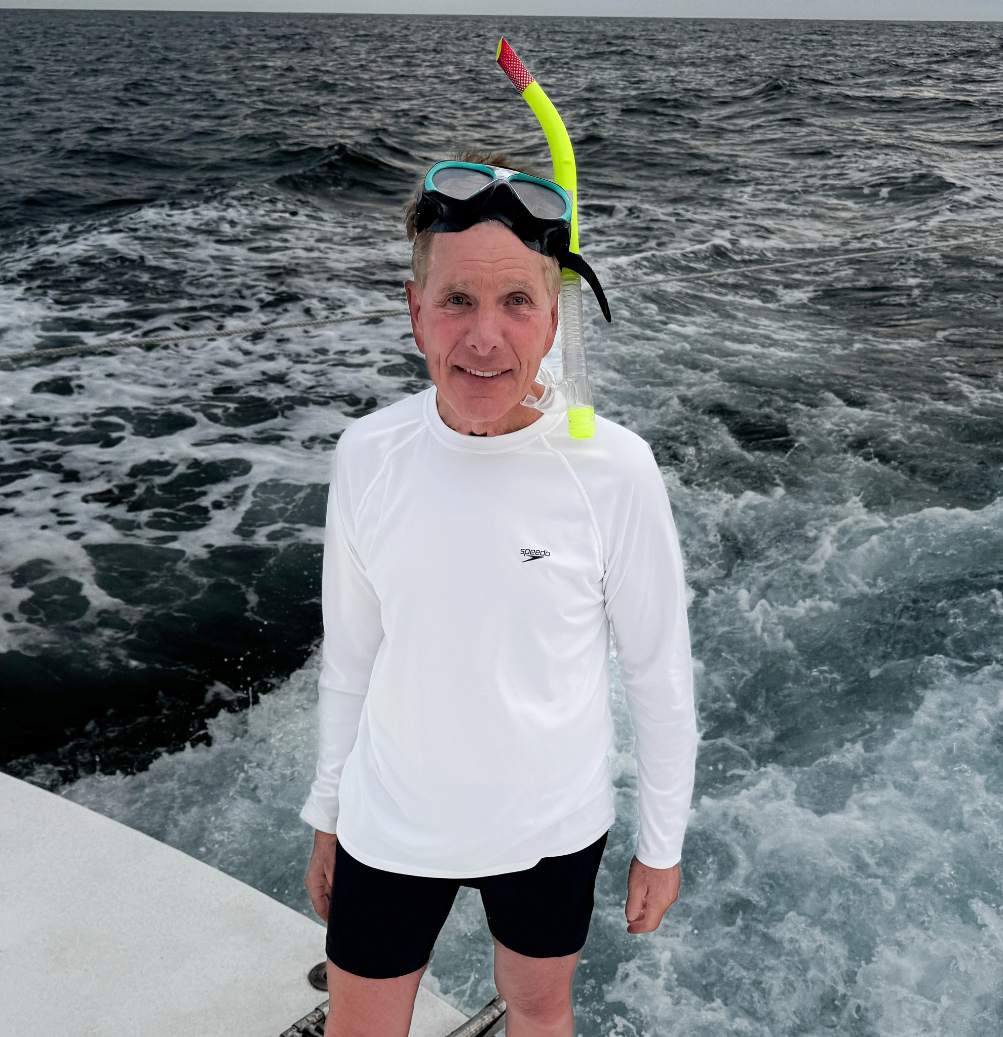 a man poses while wearing scuba gear on the back of a boat
