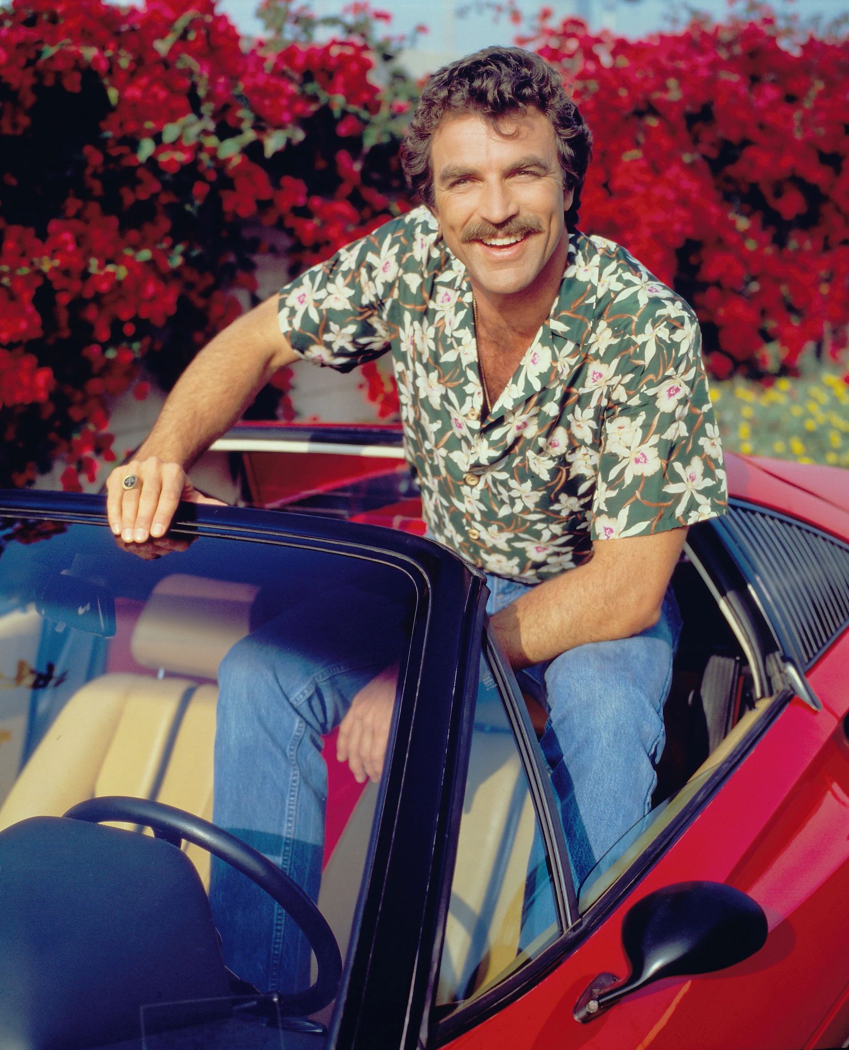 Tom Selleck sitting on his red sports car in 'Magnum, P.I.' 