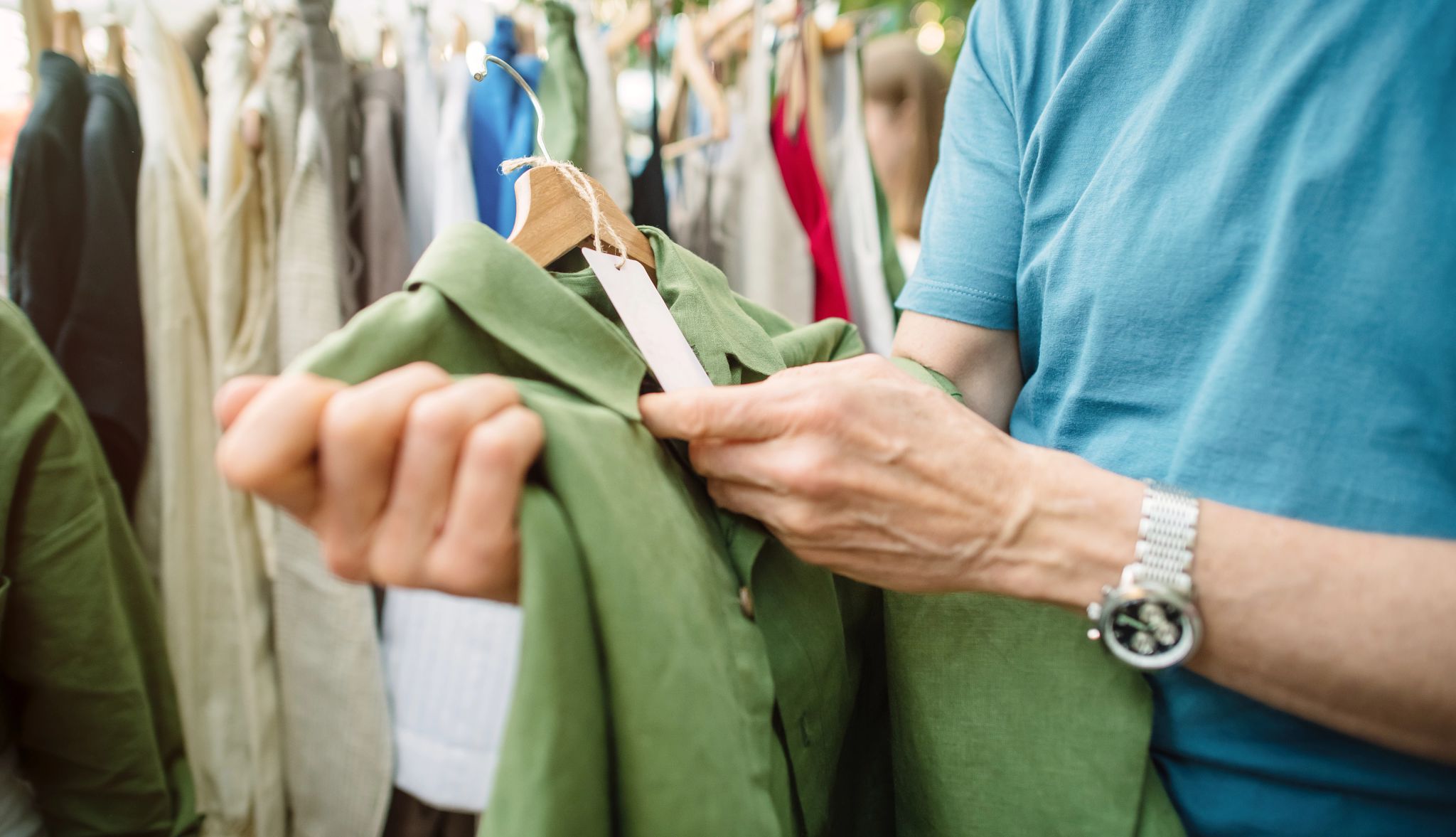Getting started with thrifting Person looking at tag on a shirt on a hanger