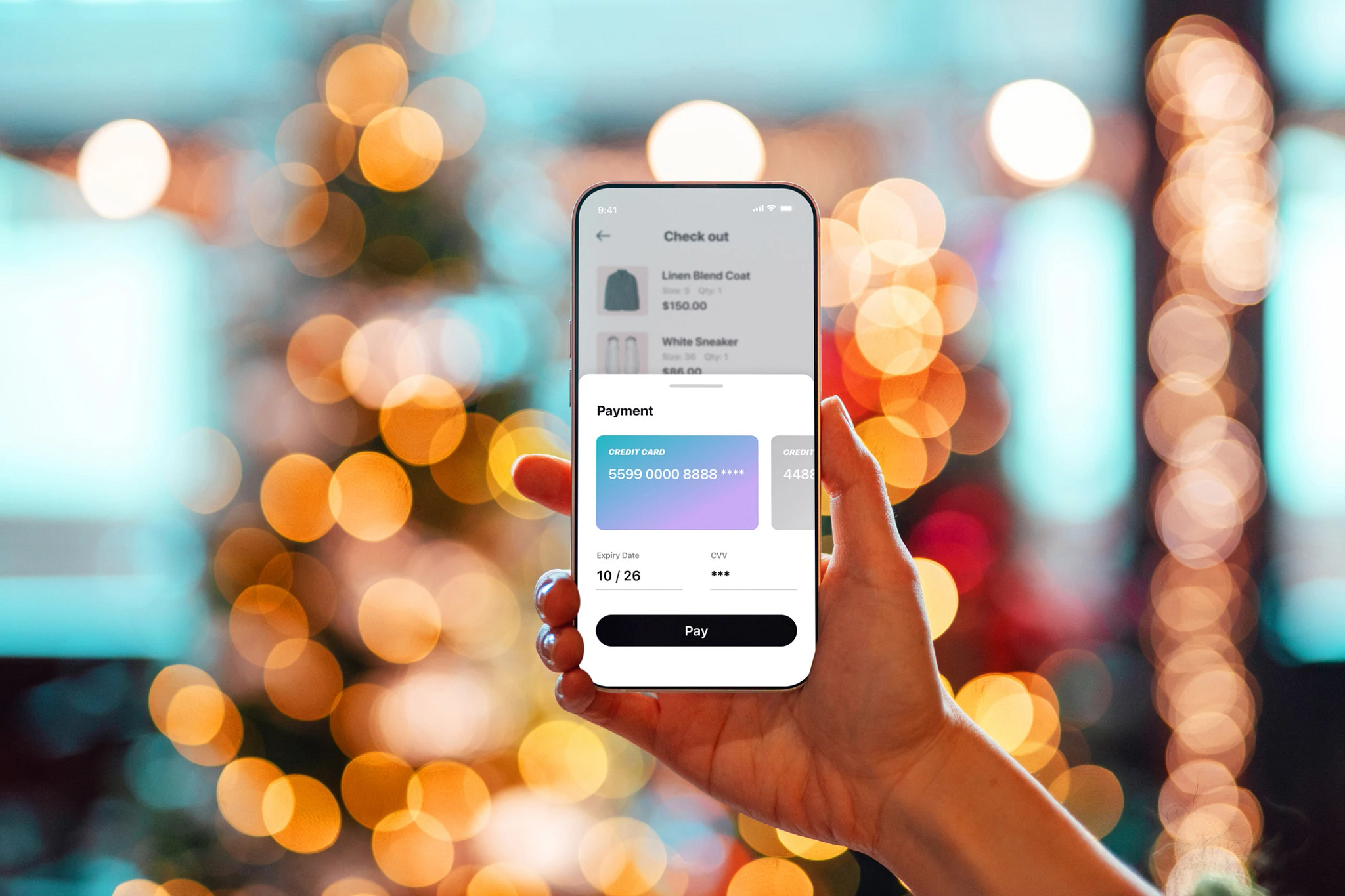Close-up of person making credit card payment with smart phone against bokeh background.
