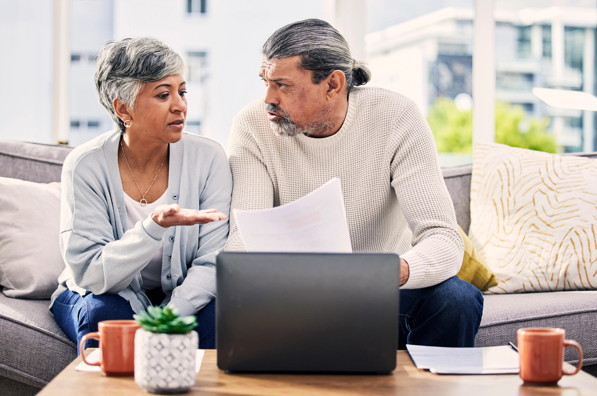 Mature indian man shaking hands with financial advisor at home. Happy smiling couple greeting broker with handshake at home. Multiethnic mid adult man and hispanic woman sealing a contract.