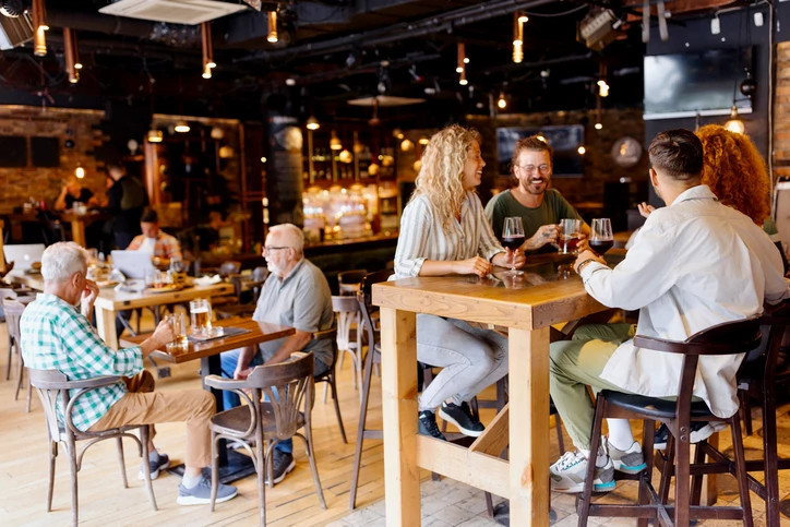 Group of people laughing and enjoying drinks and each other's company in a bar-like setting.
