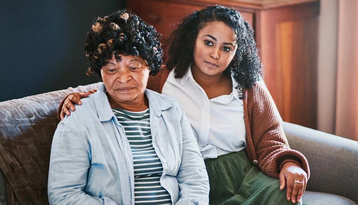 A young woman comforting her mother while sitting on a couch