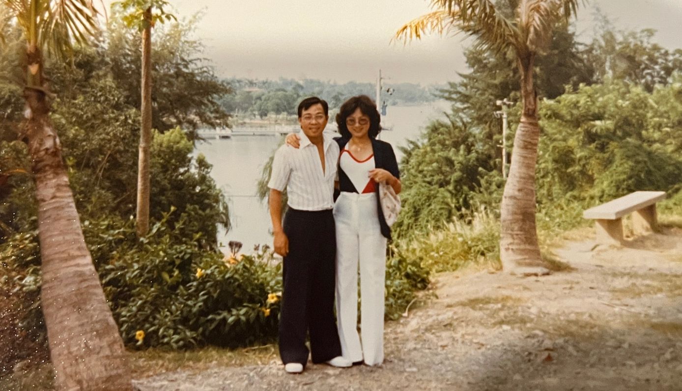 Vietnam refugees rebuild after fall of Saigon a man and woman pose on a trail. trees and bushes are behind them, with water in the distance