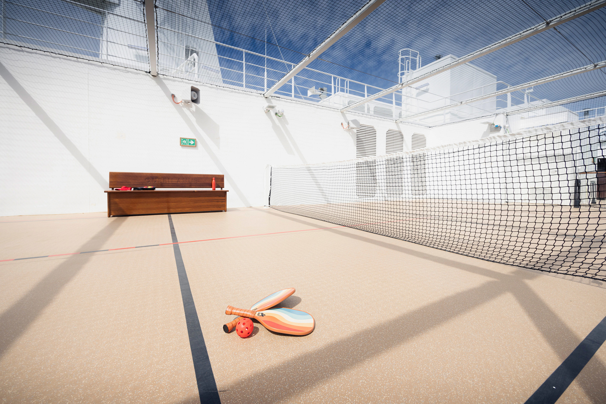 a pickleball and paddles on a court on a cruise ship