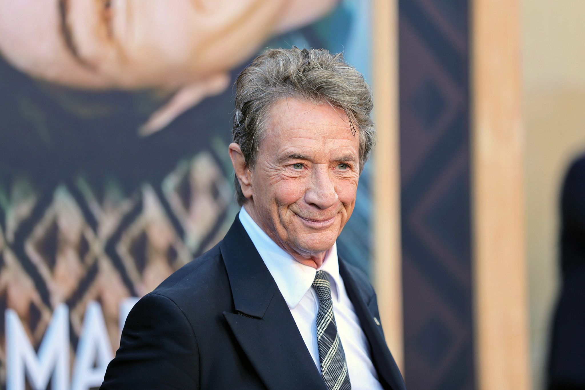 martin short wearing a black suit jacket and plaid tie