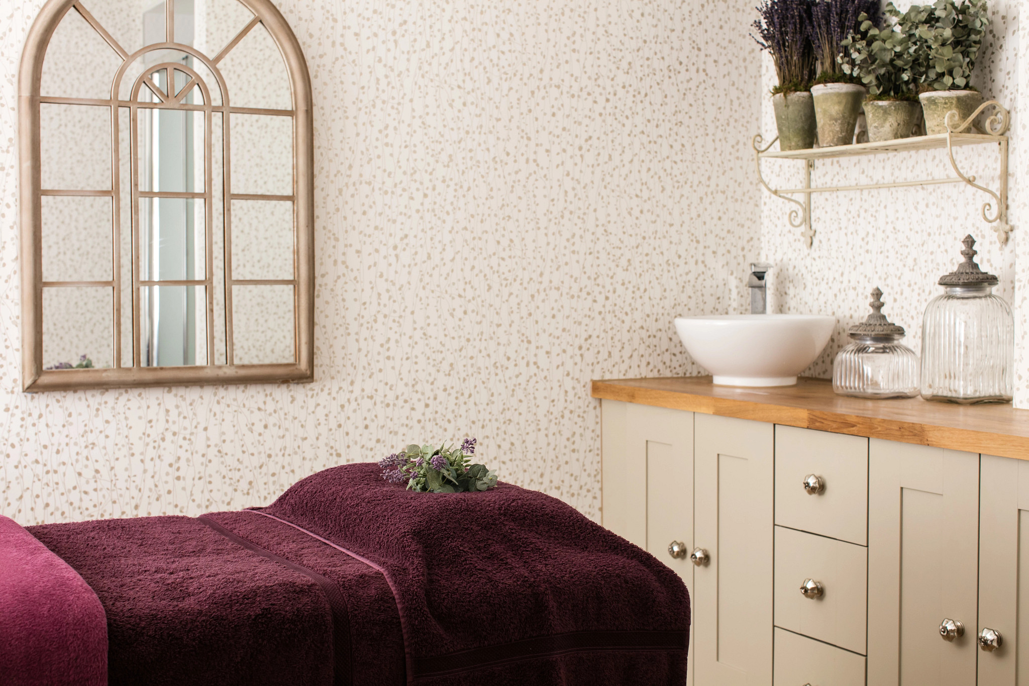a white spa room with spa table covered in dark purple towels 