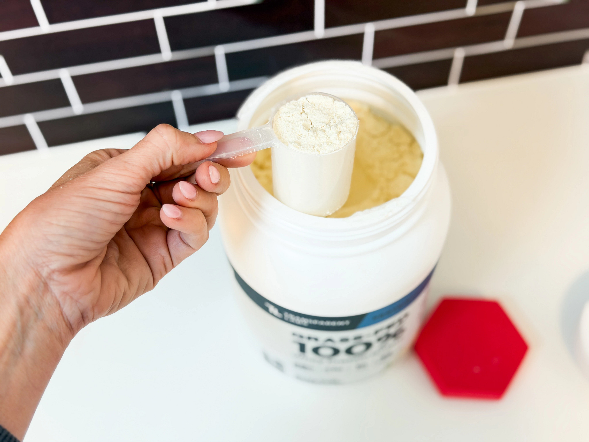 A hand scoops the Transparent Labs Whey Isolate Protein powder from the container