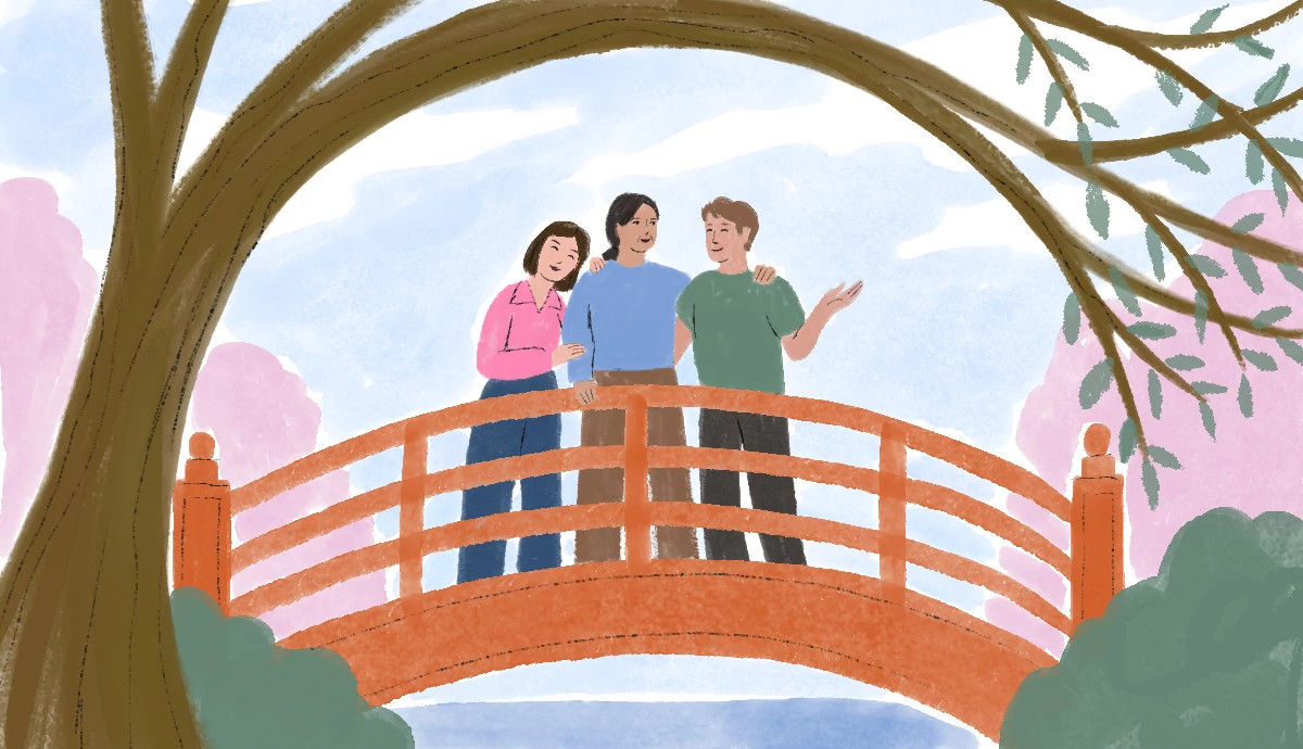 an older woman and two adult children stand on a bridge, smiling