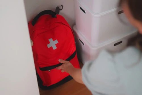 A woman grabs a red backpack or "go" bag.