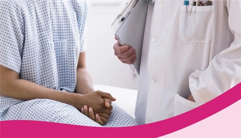 Woman In a Surgical Gown Talking to Doctor mid-body shot of a woman in a surgical gown talking to a doctor in a white lab coat holding a clipboard