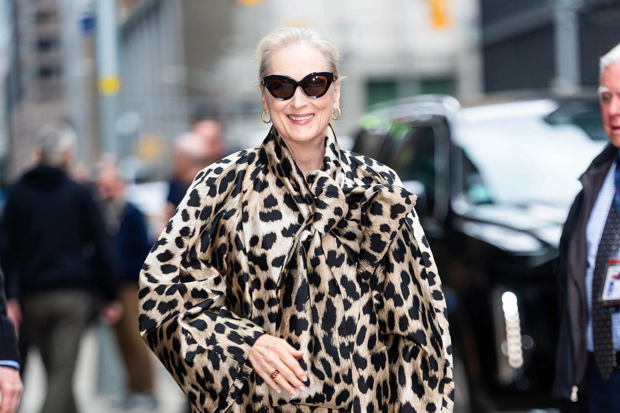 meryl streep smiling, wearing a bold leopard print jacket and sunglasses