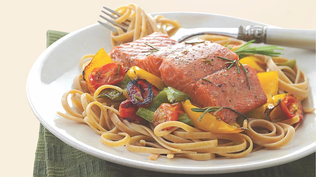 A close-up view of salmon with whole wheat pasta on a plate