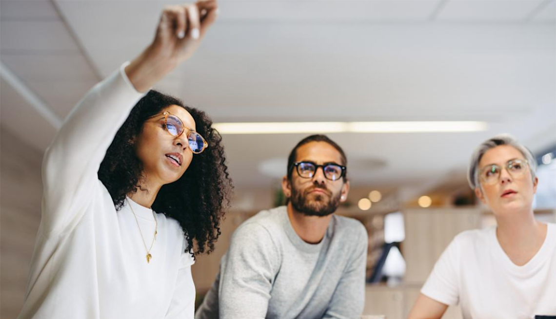 Quiz yourself to learn how helpful or harmful your own habits are A woman pointing offscreen in a work meeting with a man and another woman