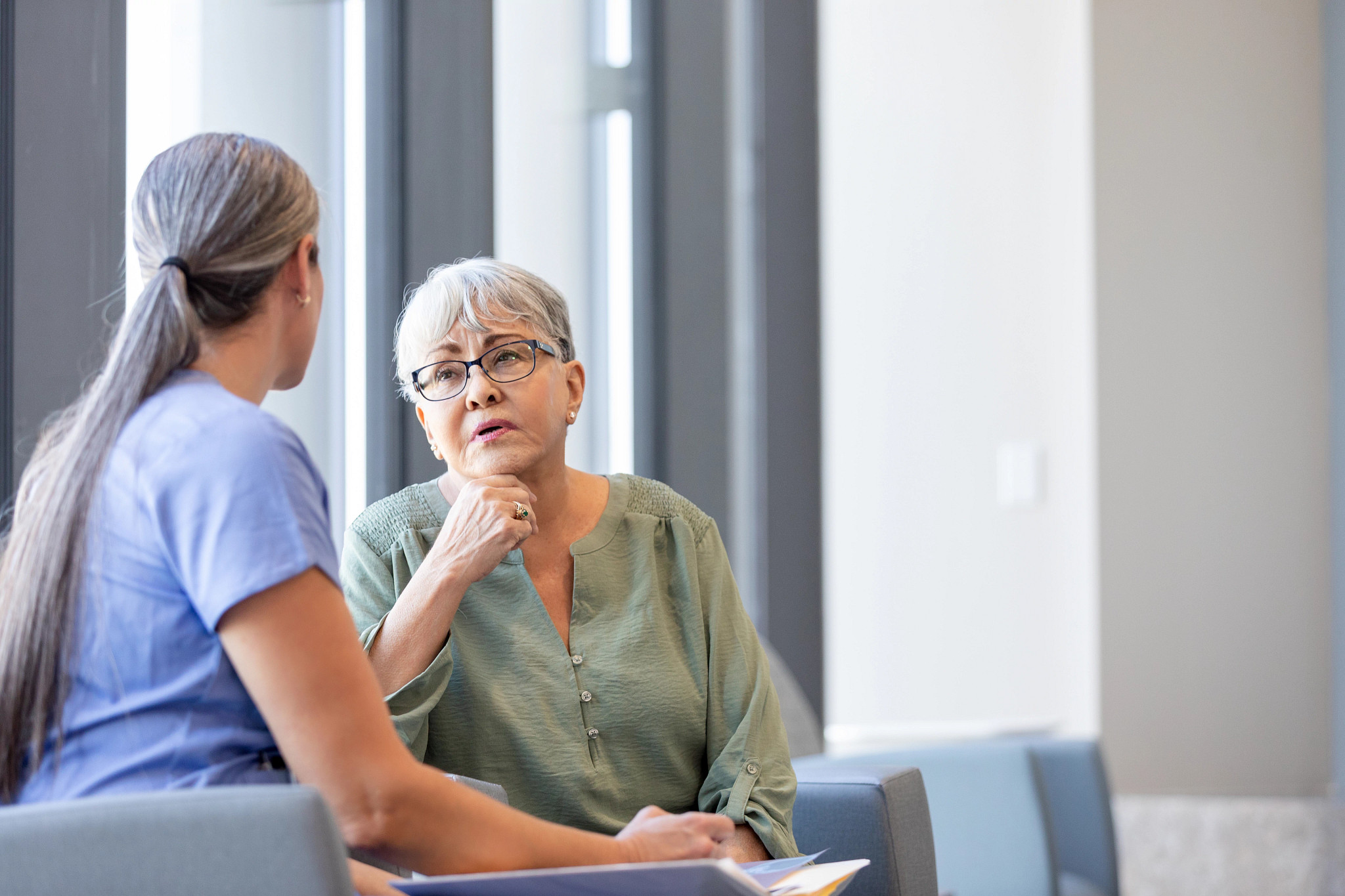 A photo shows a caregiver speaking to an older adult woman in an office waiting area