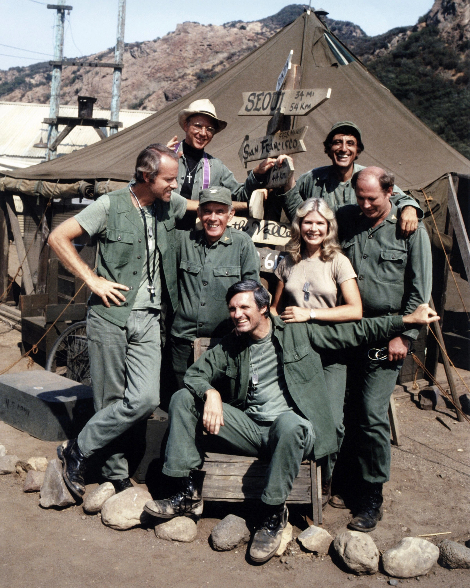 the cast of MASH posing on set for a group photo