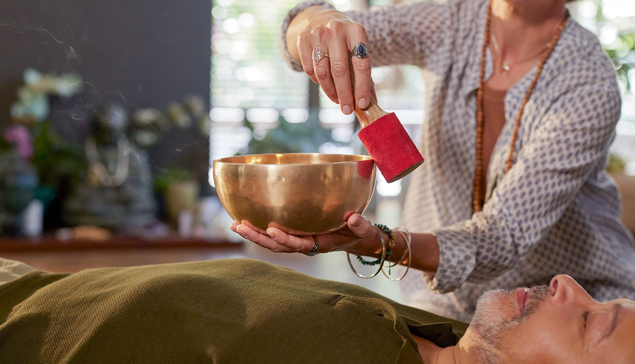 Sound Bath Benefits woman using singing bowl for sound healing