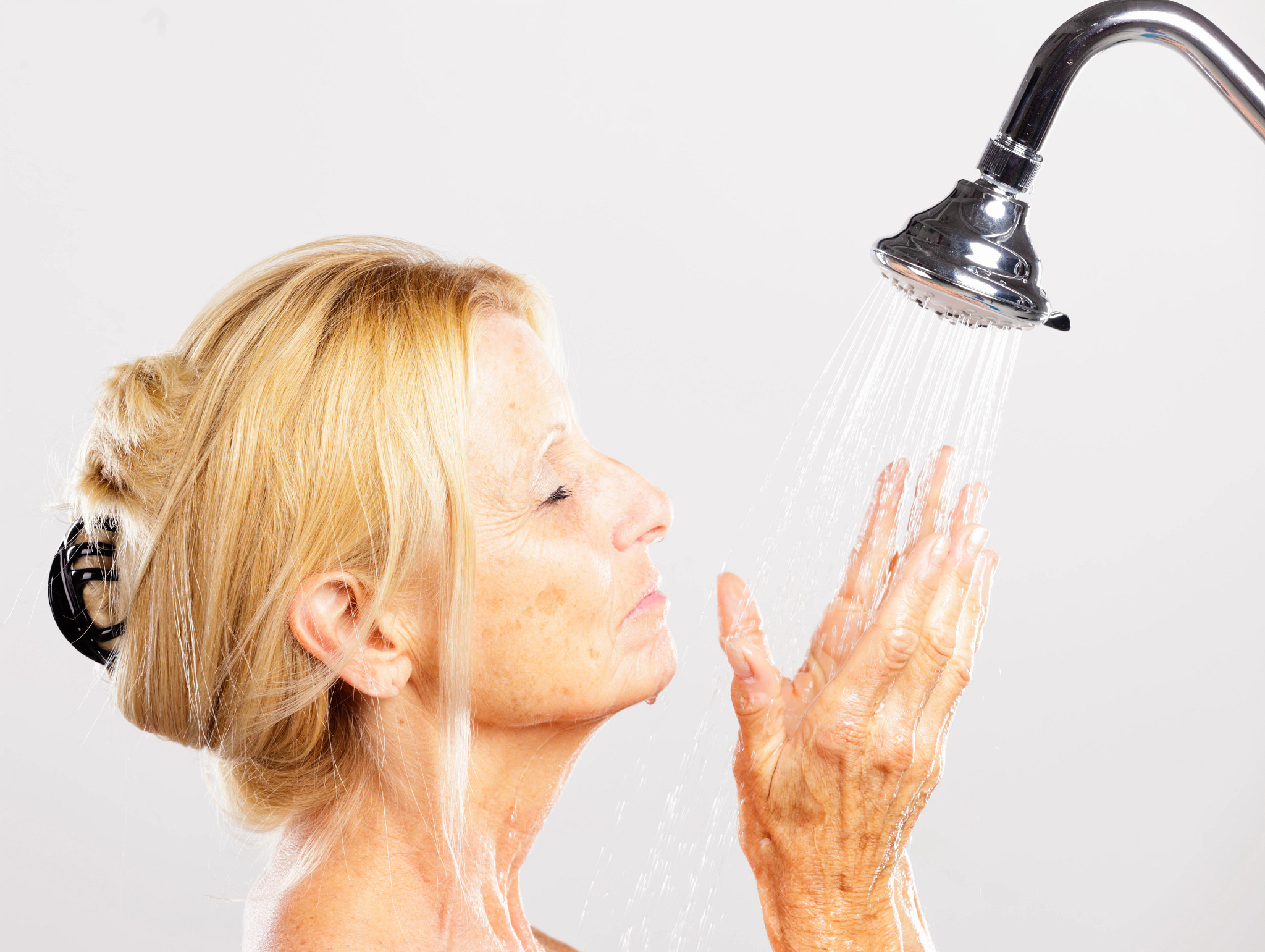 A mature woman standing in a shower.