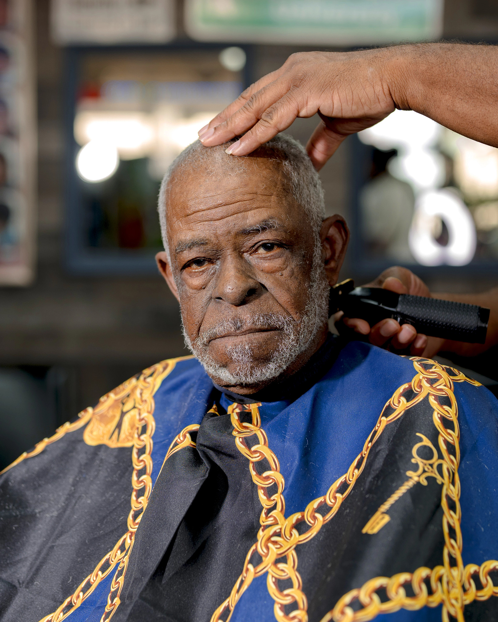 a man looks at the camera while he gets his hair cut