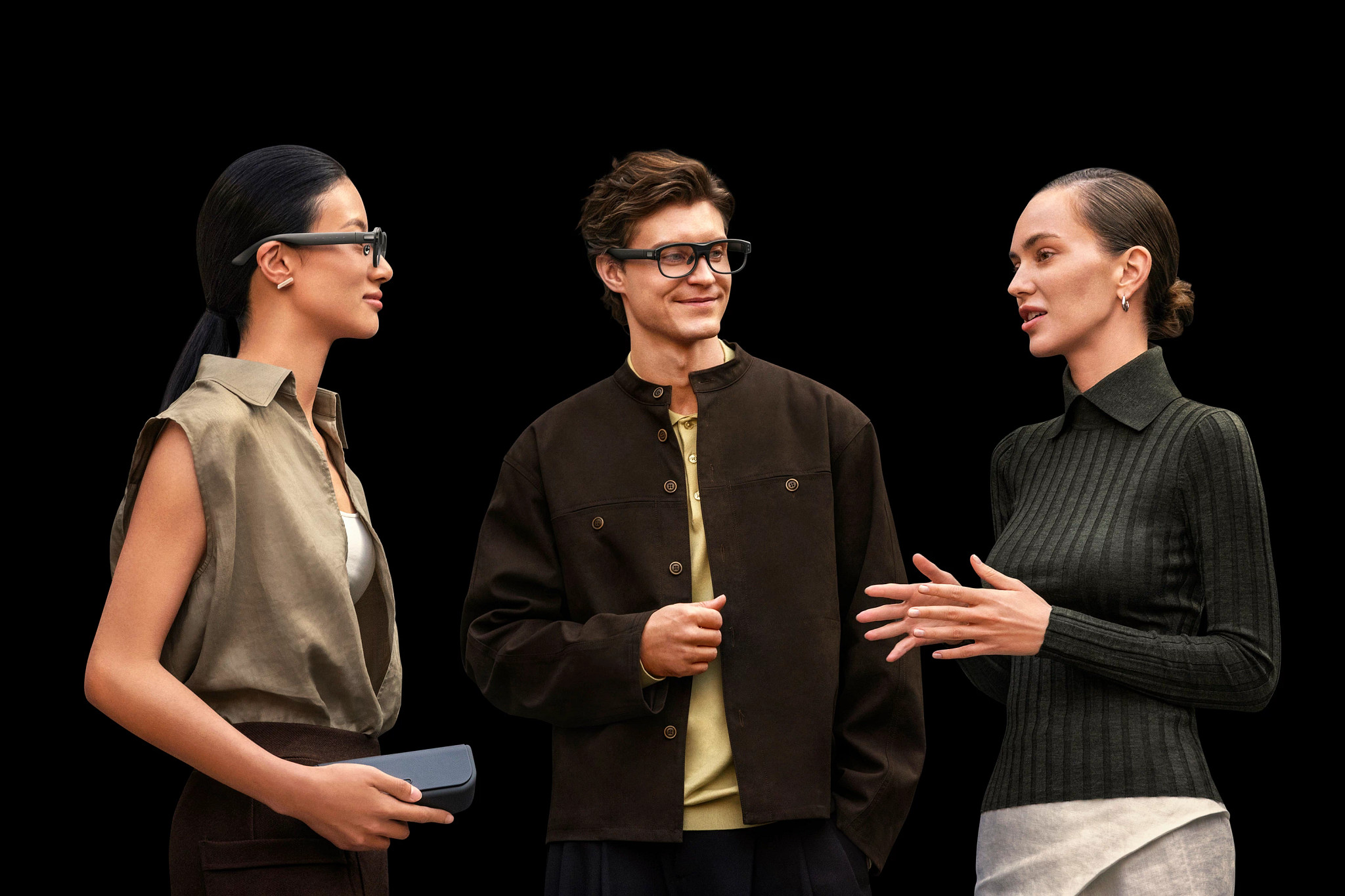 a photo shows a man and two women talking. The man and one of the women are wearing XRAI AR2 glasses