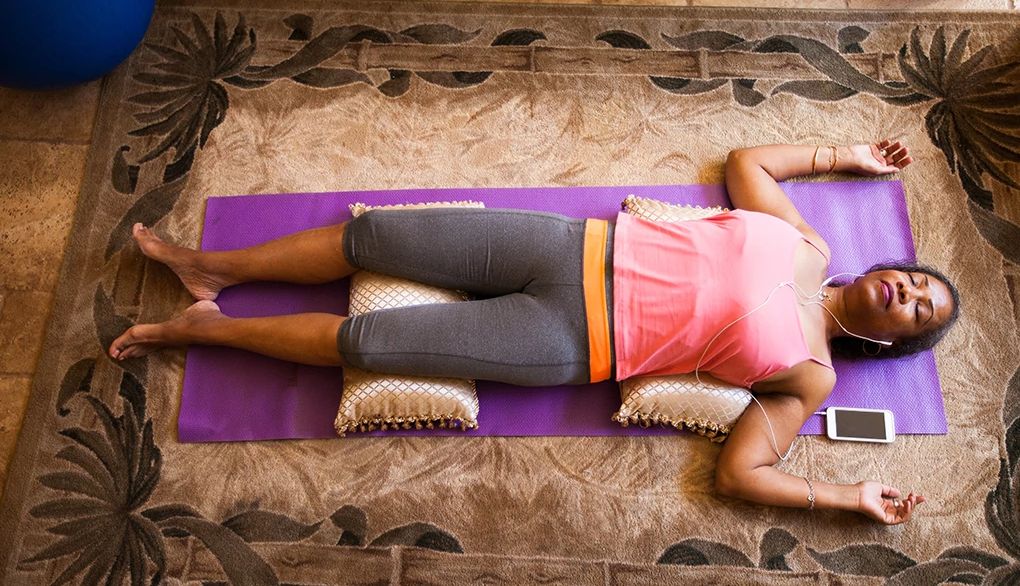 This breathing practice will tell the body it's safe to go to sleep An overhead view of a woman lying on her back meditating