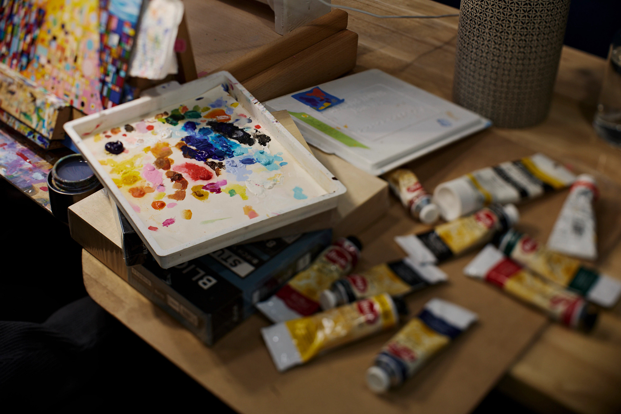 a palette with paint splotches and tubes of paint on a table