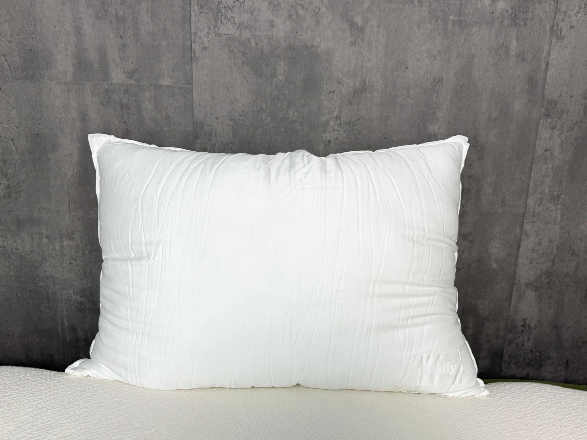 The Buffy Cloud Pillow on a bed while propped up against the wall.