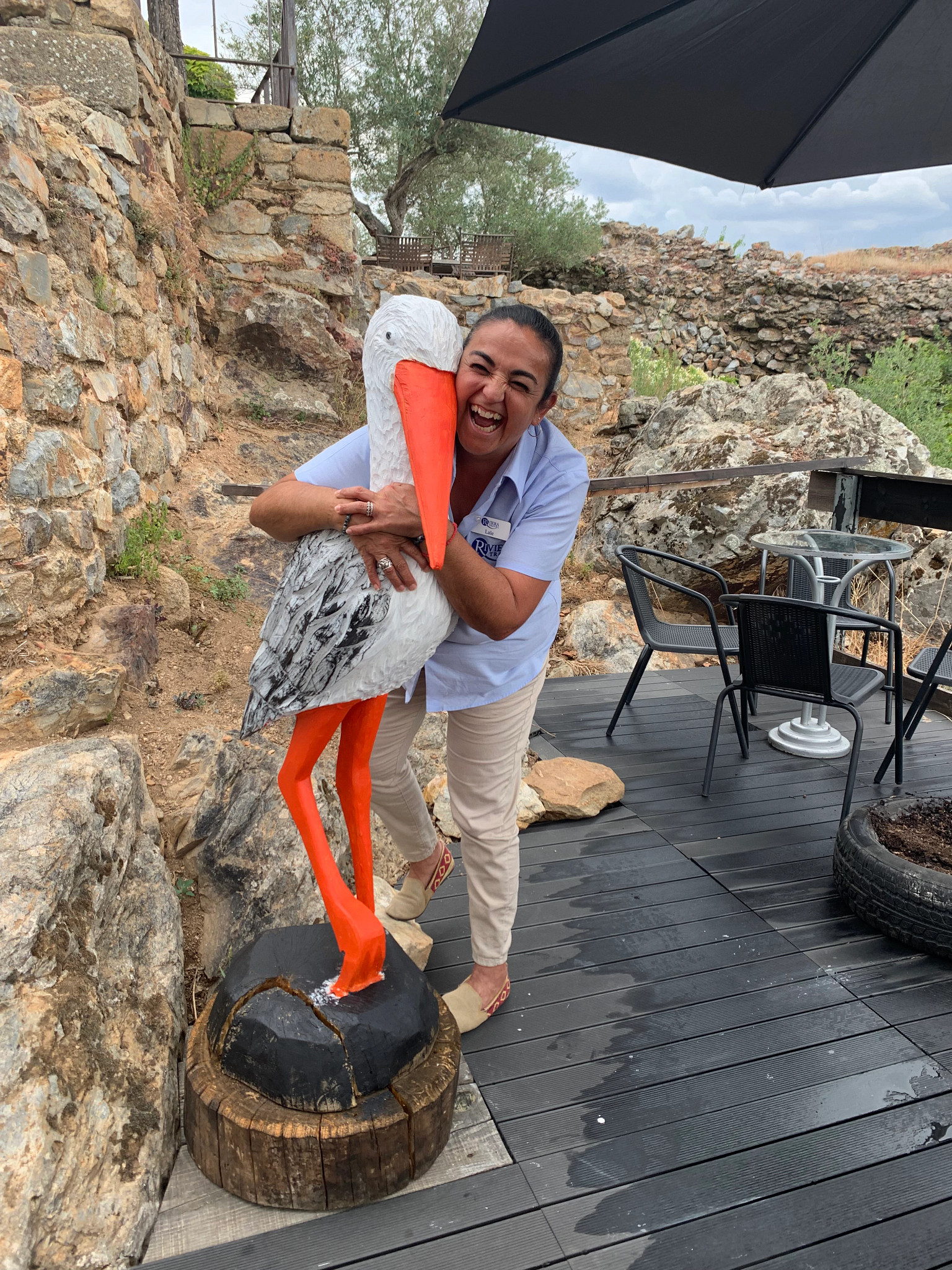 a woman smiling while hugging a pelican statue