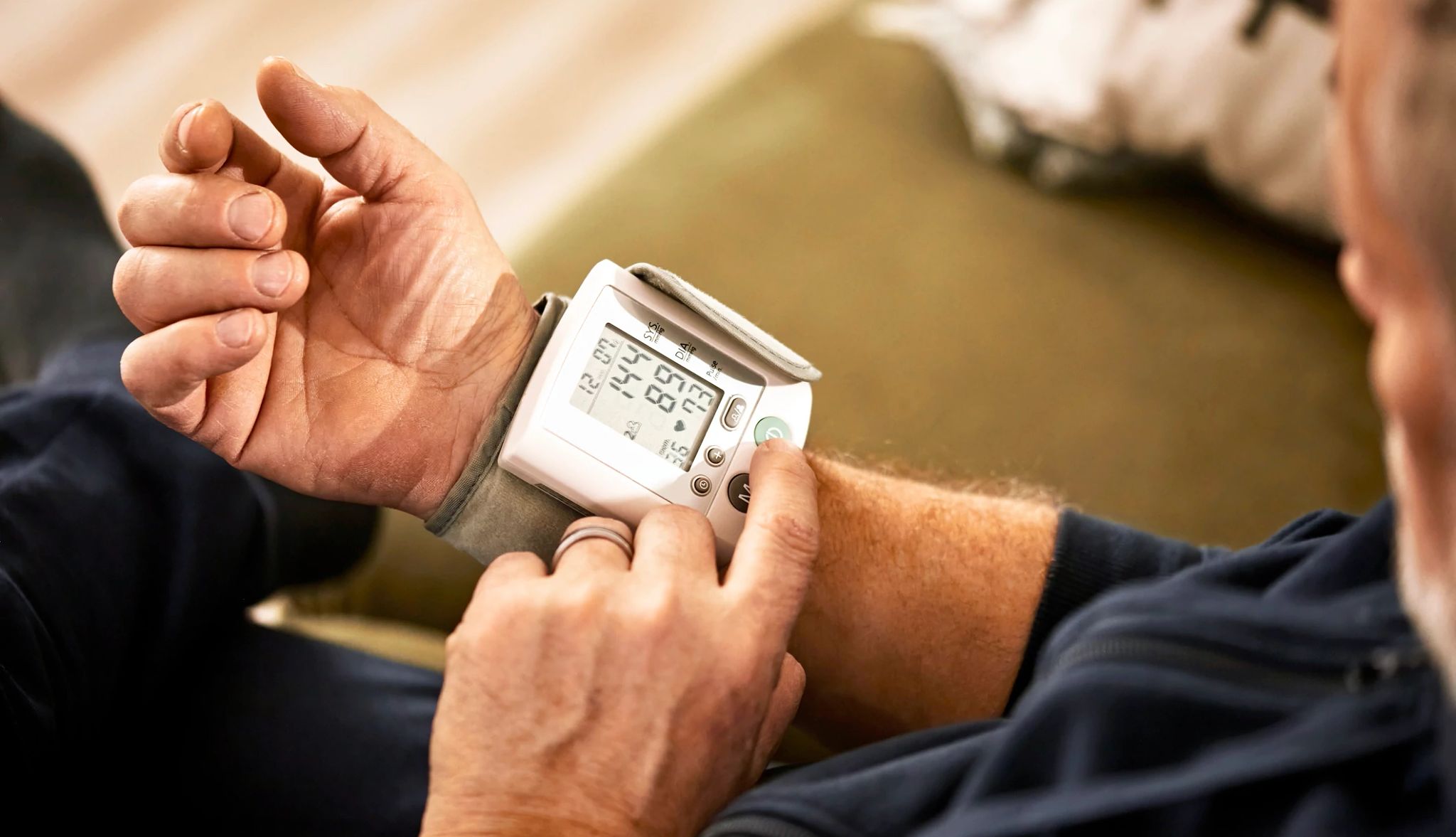 Cutting back on alcohol intake can lower high blood pressure. man checking his blood pressure with a wrist monitor
