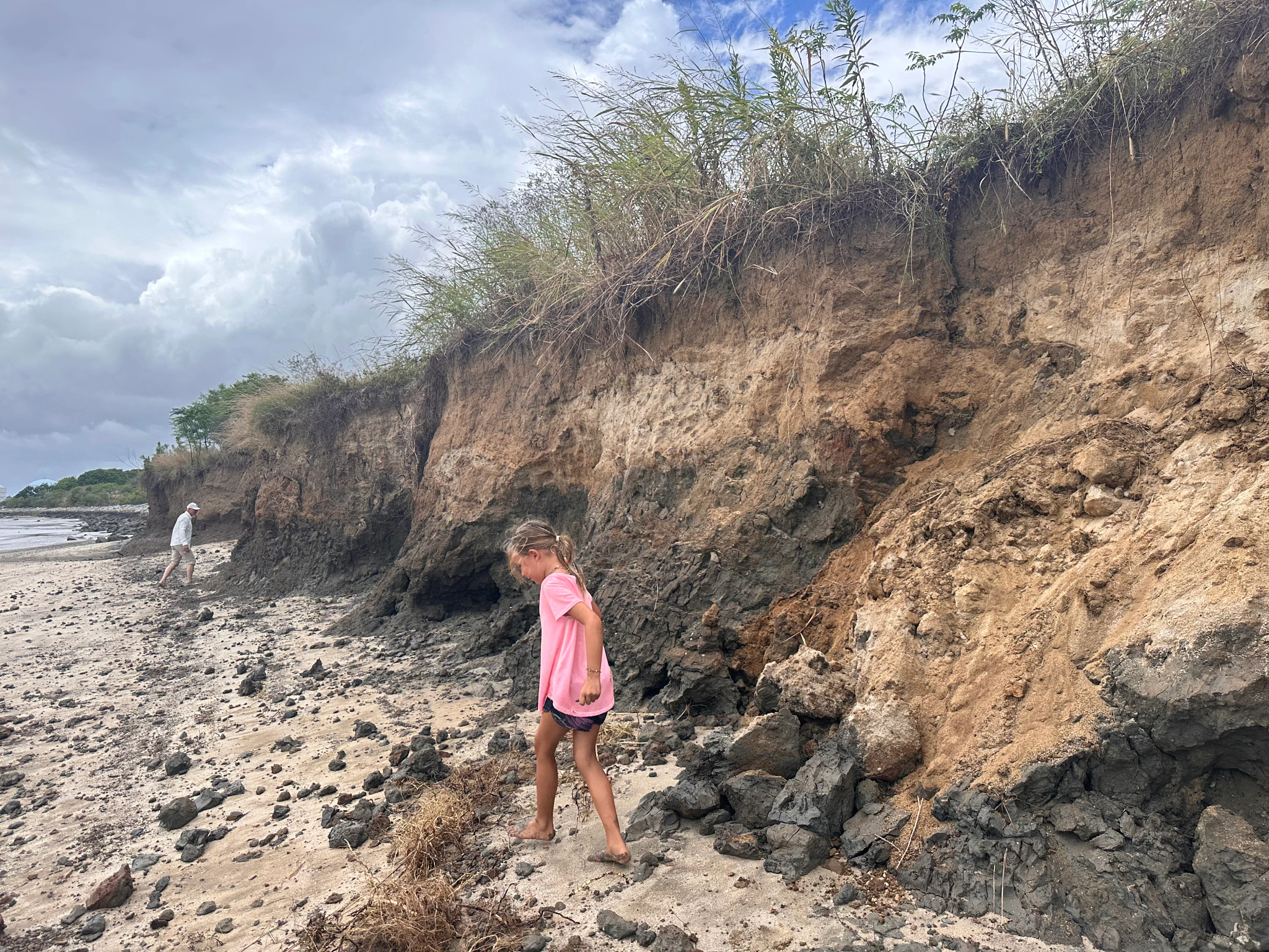 a girl and a man in the distance search for fossils