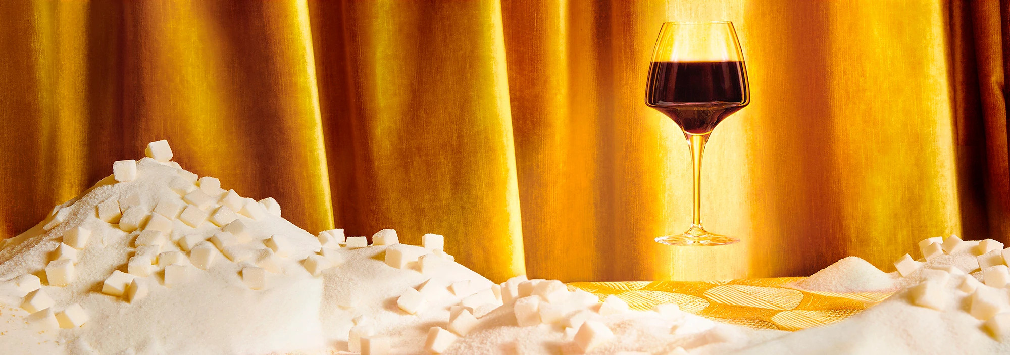 Glass of red wine hovering over mountain of sugar cubes