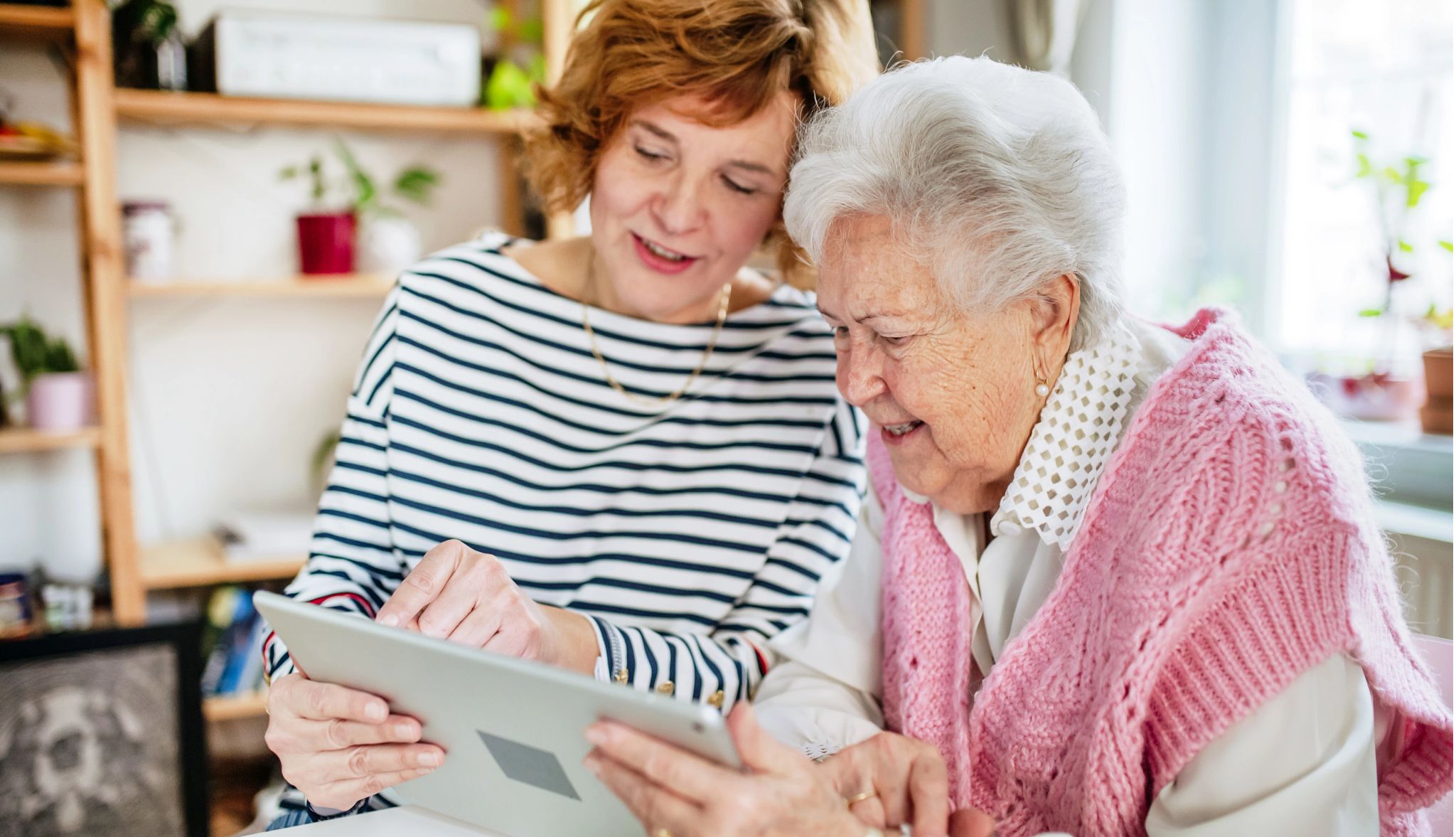 When caregivers should apply for Medicaid for a loved one a woman and an older woman look at information on a tablet