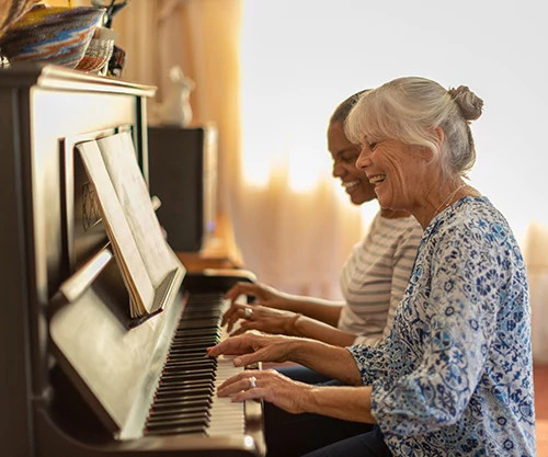 Two women playing the piano together.