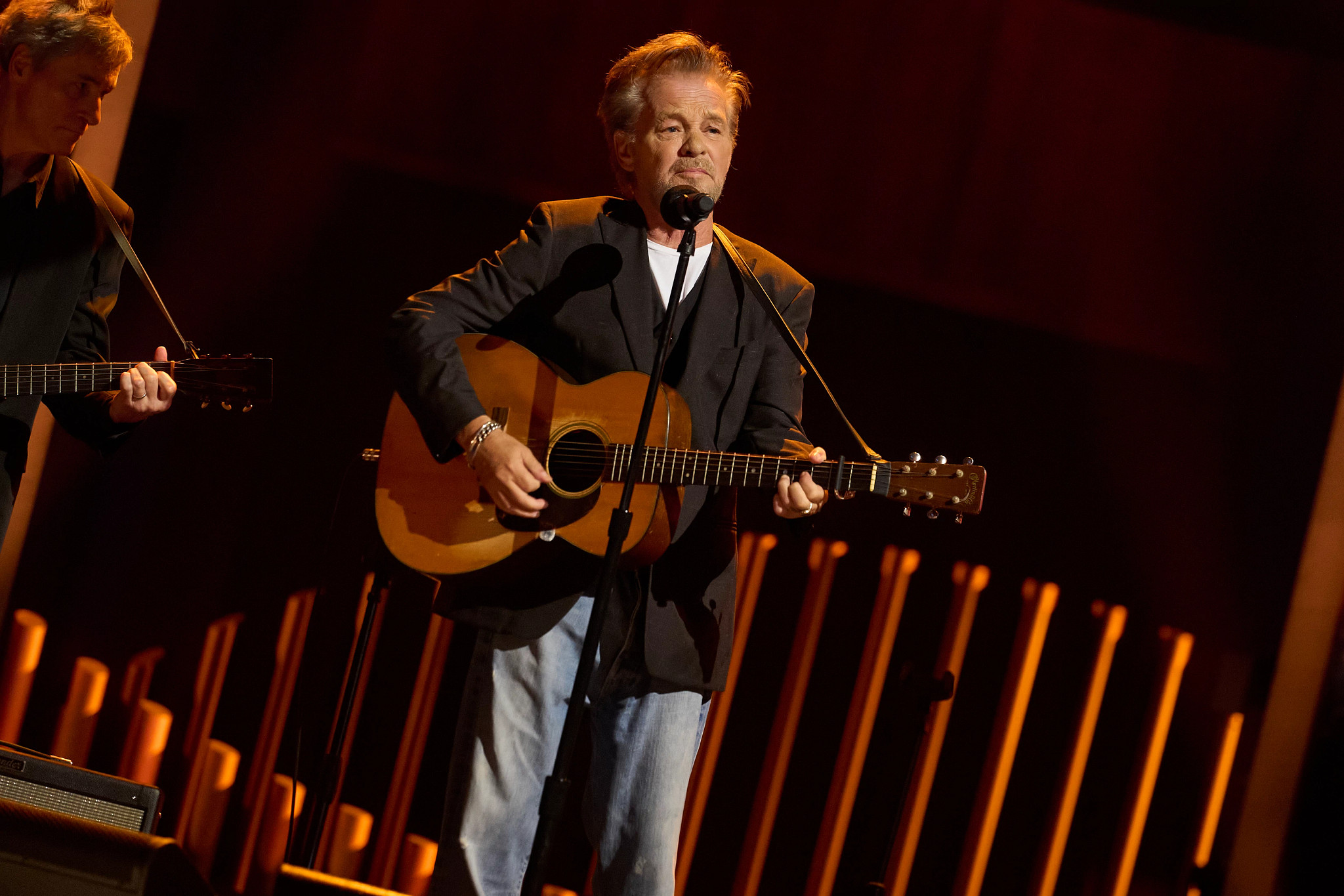 john mellencamp performing onstage with a guitar