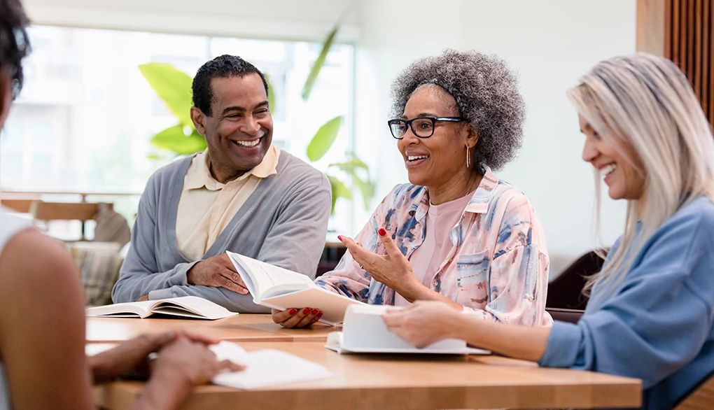 Making it social can help when learning a new language A group meeting where people with books at a table are talking to each other