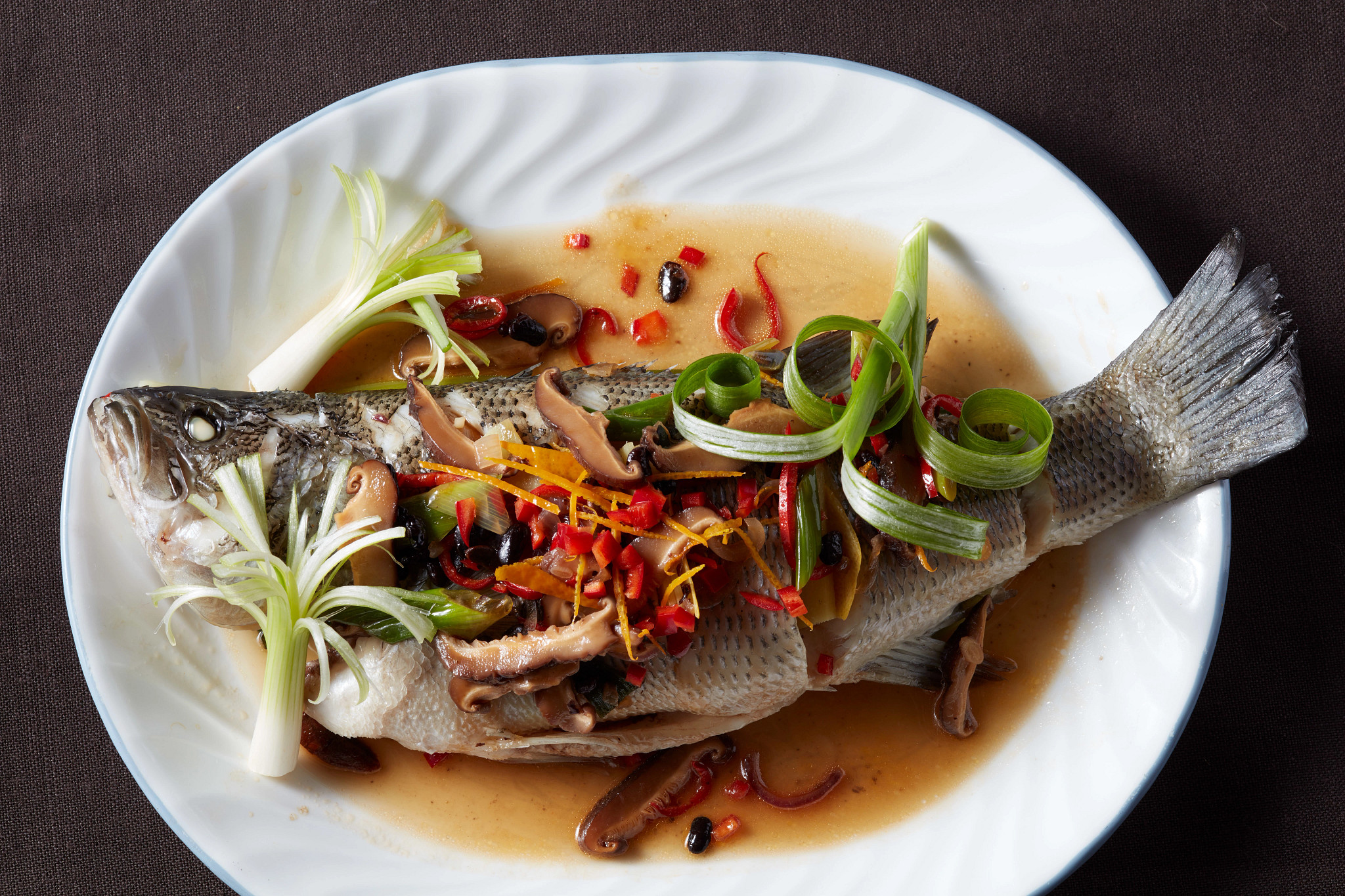 A close-up view of steamed fish with black bean sauce on a plate