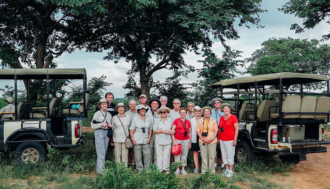 Tour group in Choe National Park, Botswana standing in front of tour vehicles.